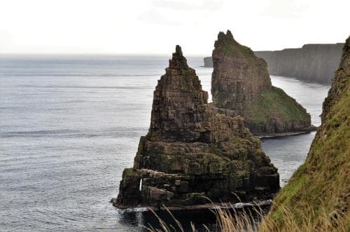 A serene coastal landscape features dramatic sea stacks rising from calm waters, ideal for scenic photography and nature exploration.