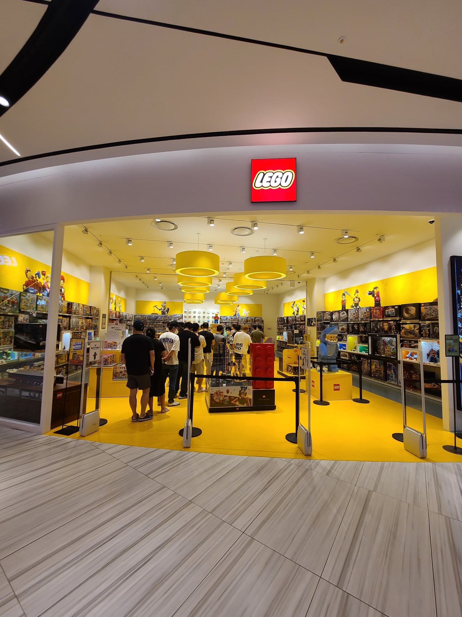 A vibrant LEGO store entrance at Shinsegae Department Store in Busan, South Korea, invites shoppers with its bright yellow decor, playful atmosphere, and neatly arranged displays, perfect for family-friendly shopping adventures.