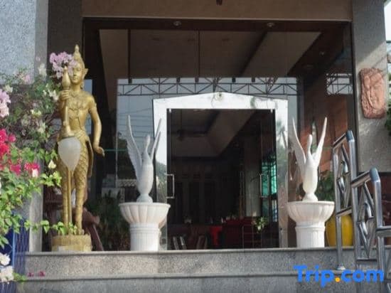 A serene entrance to an Asian-inspired restaurant features golden statues, vibrant flowers, and elegant decor, inviting travelers seeking cultural dining experiences.