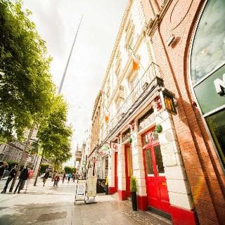 A vibrant city street lined with charming brick buildings, bustling with pedestrians under a partly cloudy sky, perfect for urban exploration and capturing the lively atmosphere of a European city center.