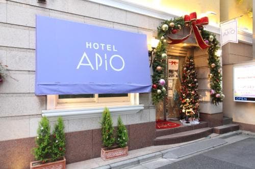 A festive entrance to Hotel Apio adorned with Christmas decorations and a purple banner, creating a warm and inviting atmosphere ideal for holiday travelers seeking cozy accommodations.