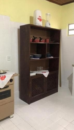 A cozy kitchen corner features a wooden shelving unit stocked with dishes and decor, set against bright yellow walls, ideal for travelers seeking a homey and functional rental space.