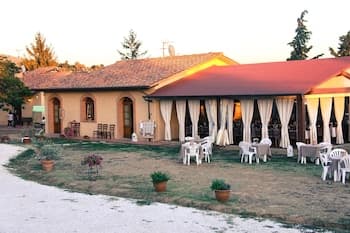 A serene countryside villa with a red-tiled roof and outdoor seating area surrounded by greenery, perfect for a tranquil getaway or event venue.