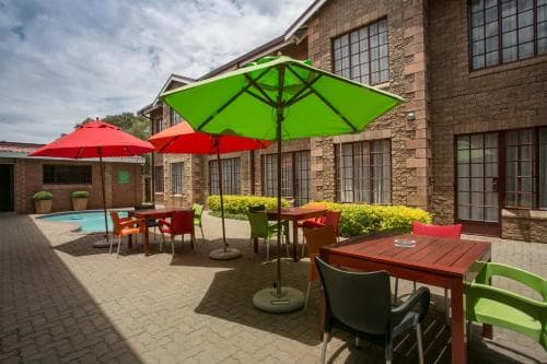 A vibrant outdoor patio with colorful umbrellas and tables invites relaxation near a serene poolside at a cozy hotel, perfect for travelers seeking a tranquil retreat.