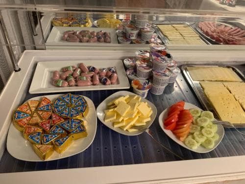 A vibrant hotel buffet scene featuring neatly arranged cheeses, yogurt cups, fresh vegetables, and colorful pastries, evoking a welcoming and indulgent breakfast atmosphere ideal for travelers seeking convenience and variety.