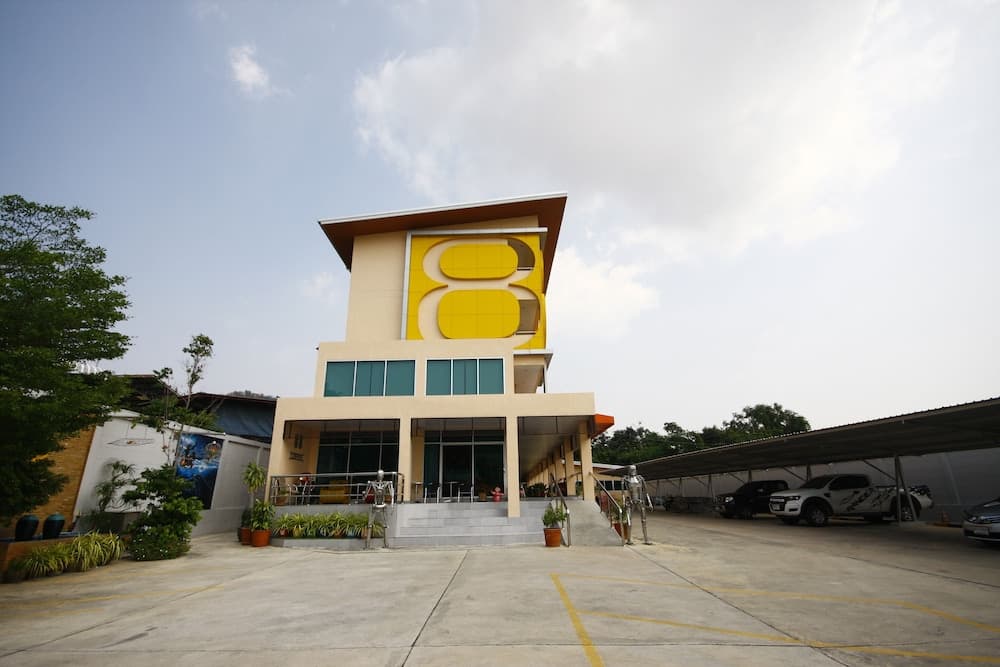 A vibrant yellow-accented building stands invitingly in an open plaza, surrounded by greenery and parked cars, ideal for travelers seeking a unique cultural or educational destination.