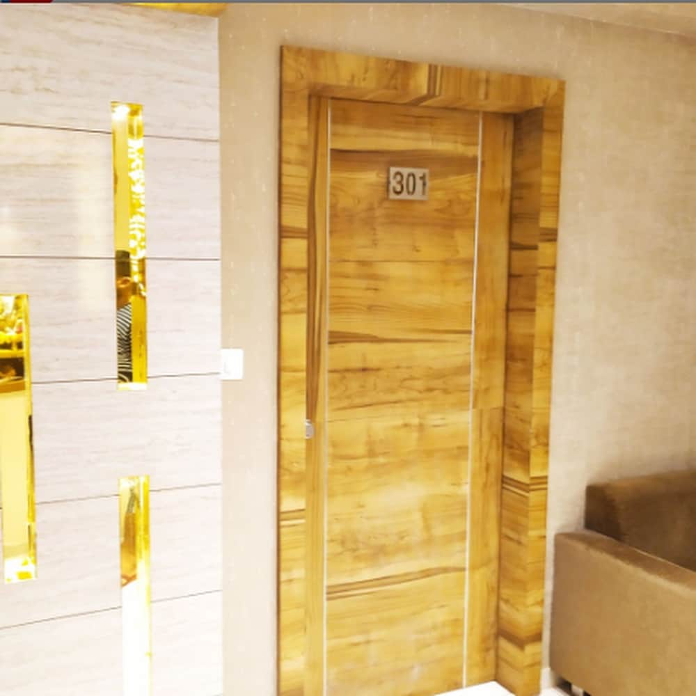 A cozy hotel room entrance features a wooden door labeled "301," flanked by golden wall accents, creating a warm and inviting atmosphere ideal for travelers seeking comfort and style.