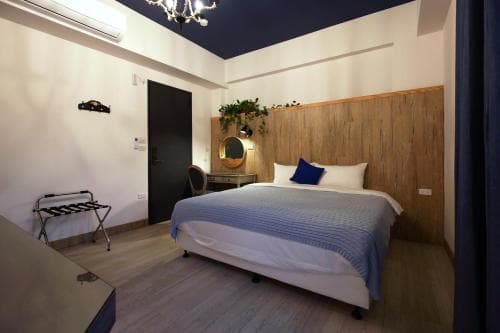A cozy hotel room with a neatly made bed, wooden headboard, and modern decor creates a serene atmosphere, ideal for travelers seeking comfort and relaxation.