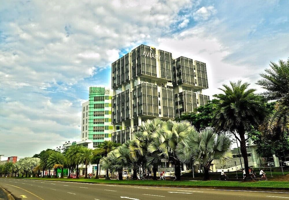 A vibrant urban street lined with lush palm trees and modern glass buildings under a partly cloudy sky, ideal for city exploration and architectural photography.