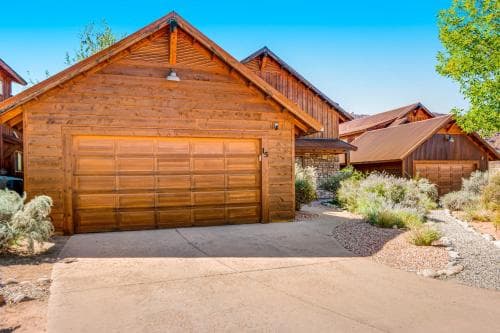 A serene suburban neighborhood features rustic wooden garages surrounded by desert landscaping under a clear blue sky, ideal for travelers seeking a peaceful retreat in a residential area.