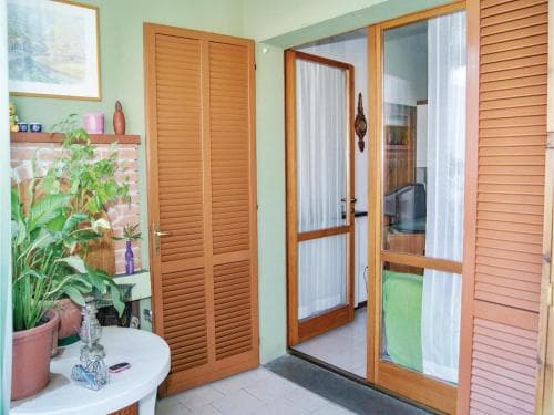 A cozy indoor entryway features wooden louvered doors, potted plants, and a small table, creating a welcoming atmosphere ideal for travelers seeking a homely accommodation experience.