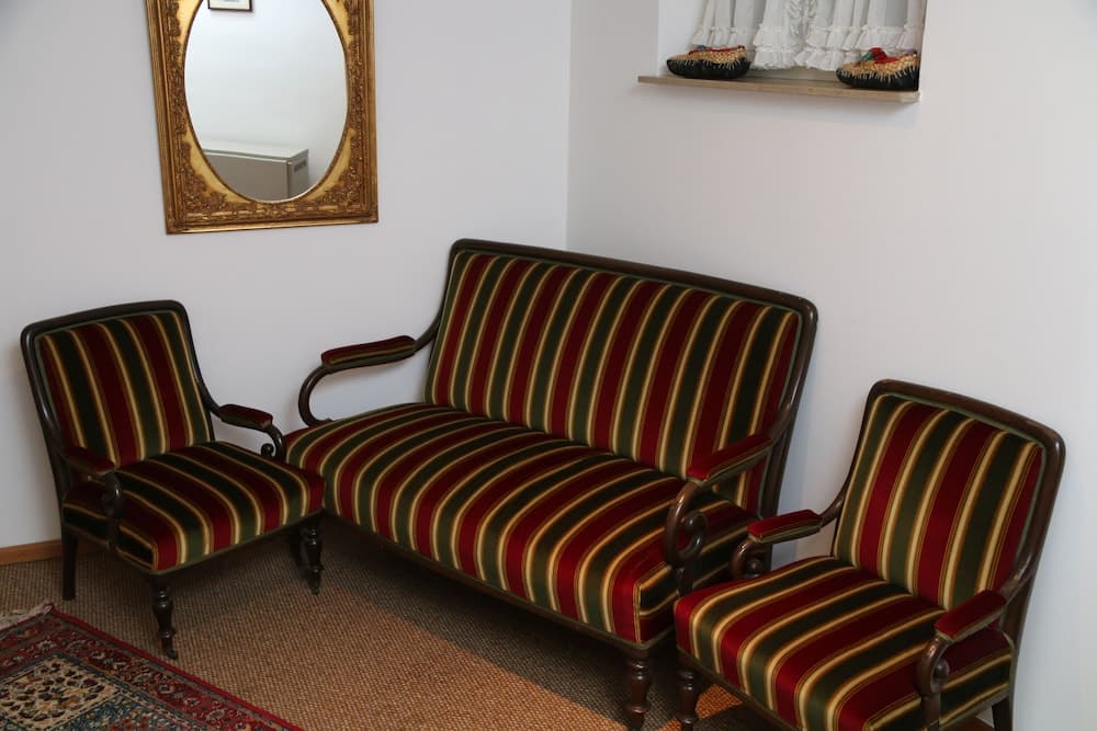 A cozy vintage lounge features striped upholstered furniture, a decorative mirror, and a window display of traditional hats, ideal for travelers seeking a nostalgic and cultural ambiance.