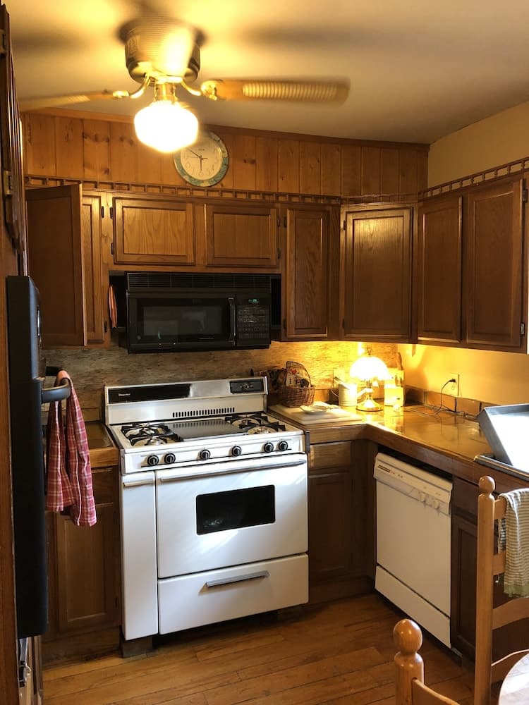 A cozy kitchen with warm wooden cabinets, a white gas stove, and soft lighting creates an inviting atmosphere perfect for a family vacation rental.