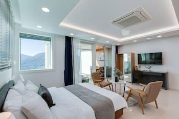 A cozy modern bedroom with a scenic mountain view through large windows, featuring stylish furniture and ambient lighting, ideal for travelers seeking relaxation and comfort in a serene retreat.