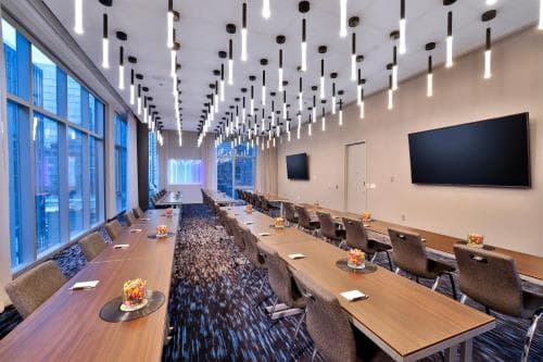 A modern conference room with sleek wooden tables, comfortable chairs, and stylish pendant lights creates an inviting atmosphere for professional meetings and collaborative work sessions.