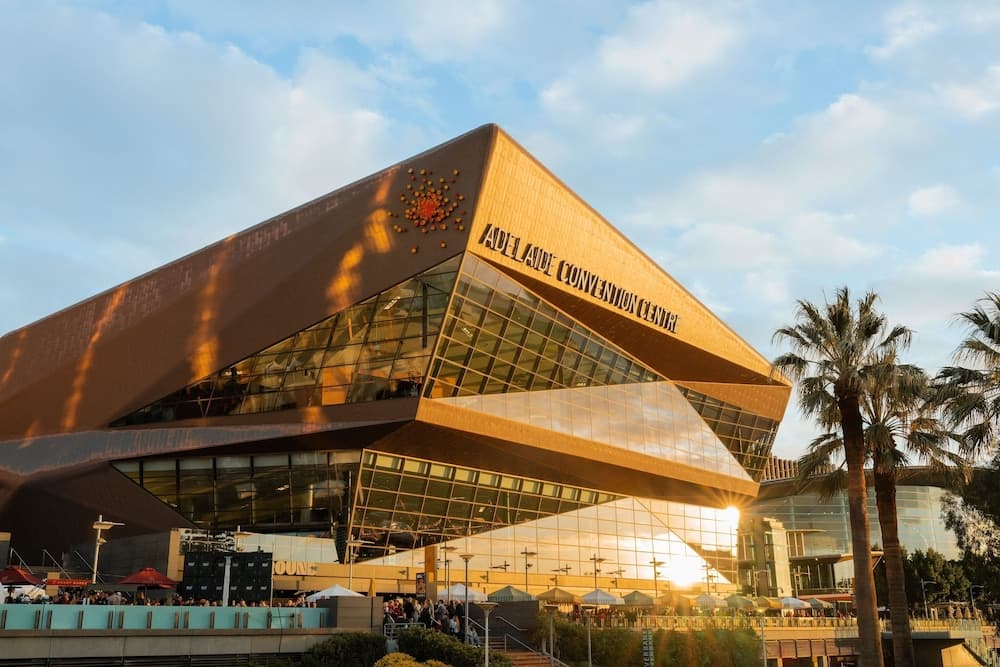 A modern convention center bathed in golden sunlight features glass panels and palm trees, creating an inviting atmosphere ideal for business travelers seeking professional events.