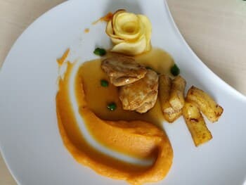 A beautifully plated gourmet dish featuring a creamy sauce, crispy potatoes, and a delicate pastry rose garnish on a modern white plate, perfect for culinary enthusiasts exploring fine dining experiences.