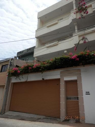 A quaint urban street scene featuring a multi-story building adorned with vibrant pink flowers, evoking a serene and welcoming atmosphere ideal for travelers seeking a cozy accommodation spot.