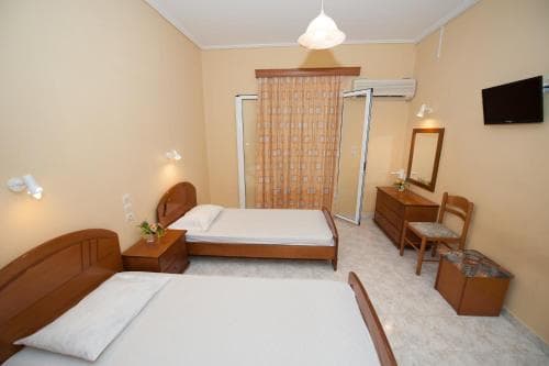 A cozy hotel room features two wooden beds, warm lighting, and simple furnishings, creating an inviting atmosphere ideal for travelers seeking comfortable accommodation.