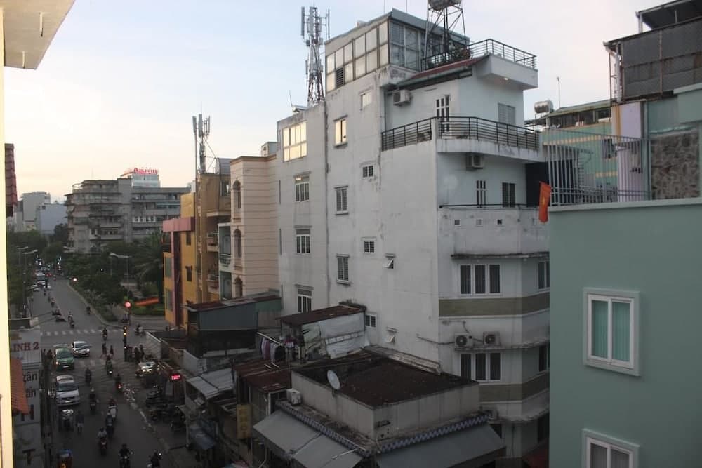 A bustling urban street scene with colorful buildings, balconies, and motorbikes captures the lively atmosphere of a Southeast Asian city, ideal for travelers exploring local culture and architecture.