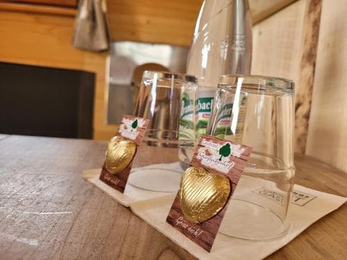 A cozy cabin interior features two glasses adorned with golden heart-shaped decorations on a wooden table, evoking a warm, rustic charm ideal for romantic getaways or intimate celebrations.