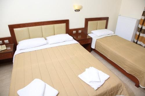A cozy hotel room features two neatly made beds with beige linens, wooden furnishings, and soft lighting, creating a welcoming atmosphere ideal for travelers seeking comfort and relaxation.