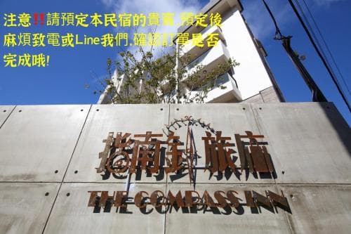 A modern urban hotel facade featuring "The Compass Inn" signage under a clear blue sky, ideal for travelers seeking stylish accommodations in a bustling cityscape.