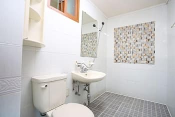 A clean, modern bathroom with white tiled walls, a mosaic art piece, and a sink with a mirror above it offers a serene space ideal for travelers seeking comfort and style in accommodations.