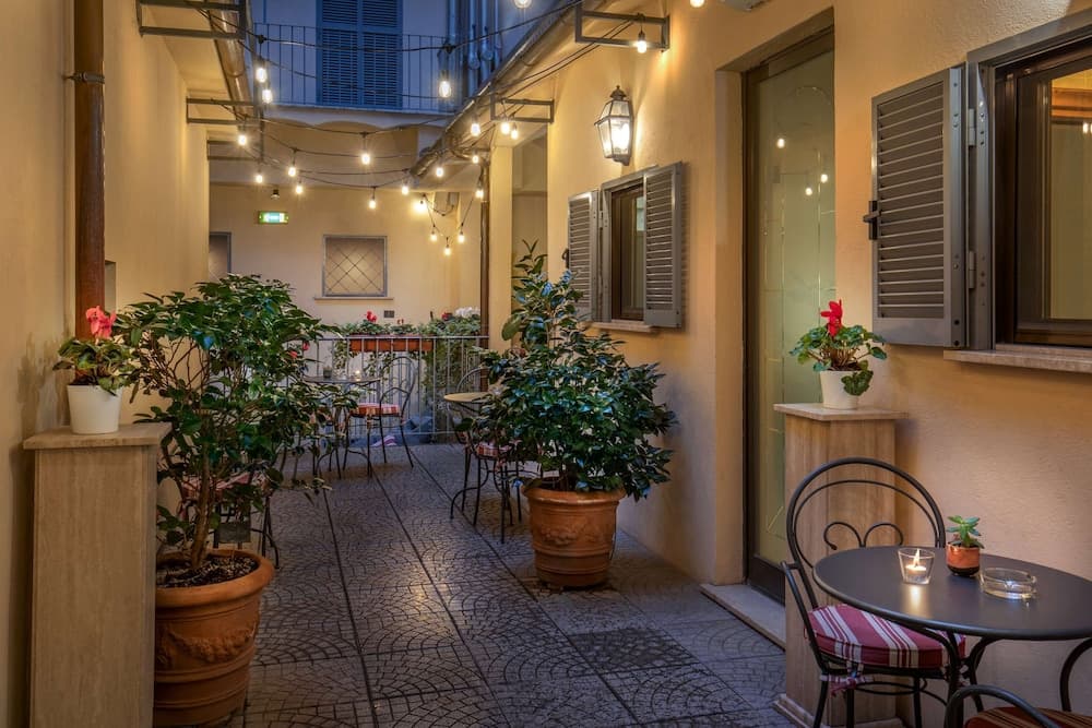A cozy outdoor patio adorned with string lights, potted plants, and small tables creates an inviting evening ambiance perfect for intimate dining or relaxing with a drink.
