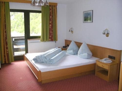 A cozy hotel room with a neatly made bed, wooden furnishings, and a scenic view through the window, ideal for travelers seeking comfort and relaxation in a serene setting.