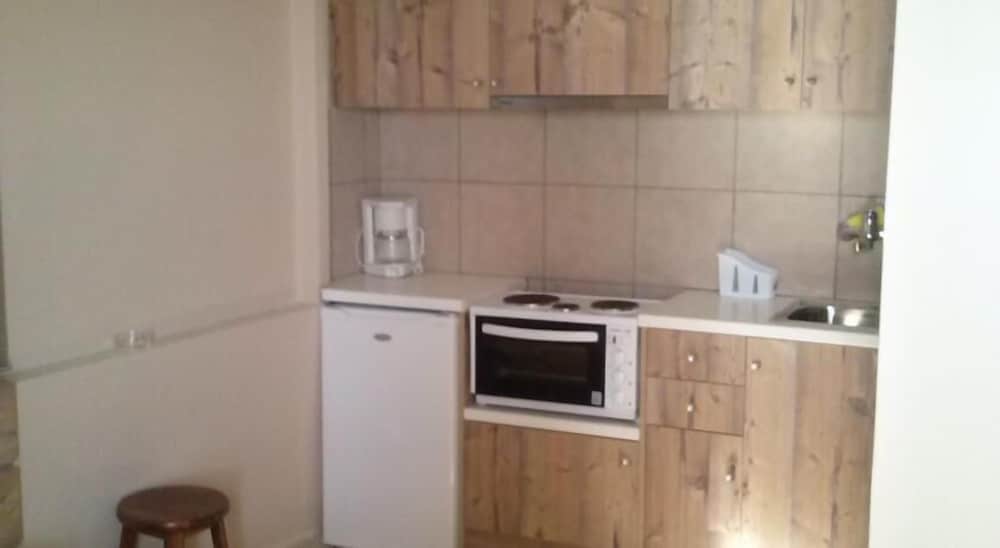 A cozy, compact kitchenette with wooden cabinets, a small fridge, microwave oven, and sink offers a practical space for travelers seeking self-catering accommodations.