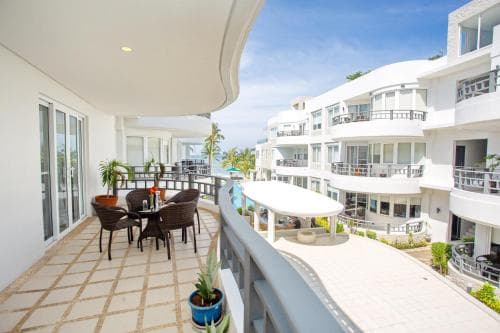 A serene balcony overlooks a luxurious apartment complex with palm trees and a clear blue sky, ideal for vacation rental listings showcasing tropical getaways.