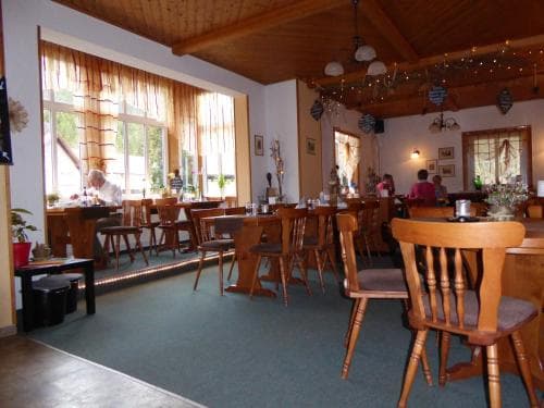 A cozy indoor café with wooden furniture, large windows letting in natural light, and festive decorations creates a warm and inviting atmosphere perfect for travelers seeking a relaxing dining experience.