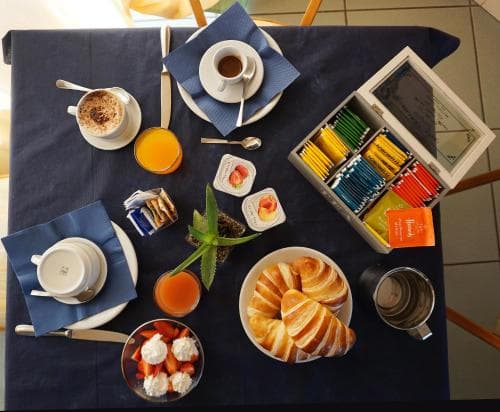 A cozy breakfast spread on a navy blue tablecloth features croissants, fresh fruit, coffee, and juice, creating an inviting morning ambiance perfect for a relaxing hotel stay or bed-and-breakfast experience.