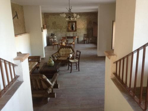 A cozy indoor lounge area with rustic wooden furniture, tiled floors, and a staircase, evokes a warm, inviting atmosphere ideal for travelers seeking relaxation in a charming retreat setting.