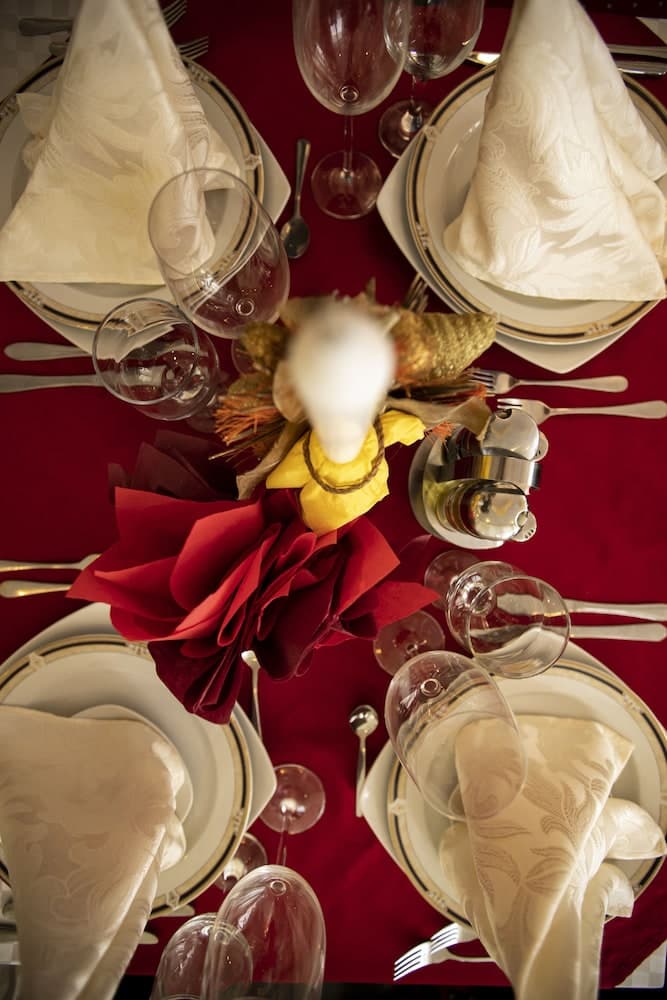 An elegantly set dining table with a vibrant red tablecloth, white napkins, and colorful floral centerpieces creates a festive and sophisticated atmosphere ideal for special occasions or upscale events.