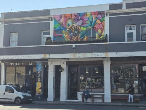 A vibrant mural adorns the facade of a quaint urban storefront, creating an inviting atmosphere for shoppers and passersby to explore local boutiques and cafes.