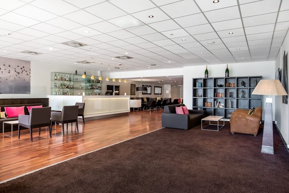 A modern hotel lobby features sleek furniture, a well-stocked bar, and ambient lighting, creating a cozy yet sophisticated atmosphere ideal for travelers seeking relaxation and comfort.