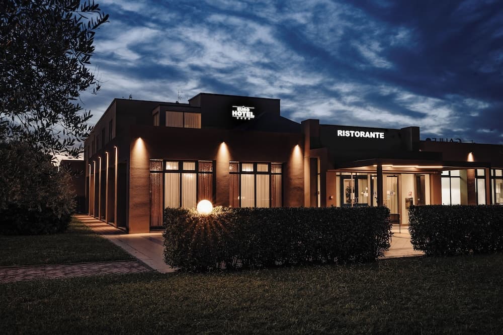 A serene evening view of a modern hotel and restaurant illuminated by warm lights under a starry sky, ideal for travelers seeking a cozy accommodation experience.