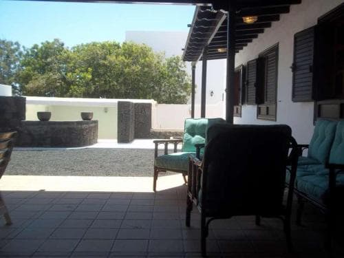 A serene patio with tiled flooring, cozy seating, and lush greenery offers a tranquil retreat, ideal for travelers seeking relaxation in a private villa setting.