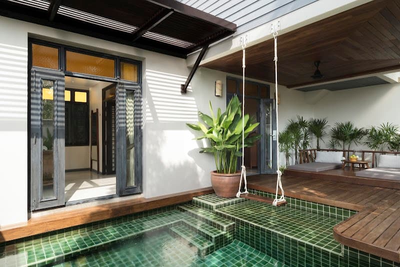 A serene tropical resort scene featuring a private pool villa with lush greenery, a hanging swing, and open doors inviting relaxation, ideal for luxury travelers seeking tranquility in Thailand.