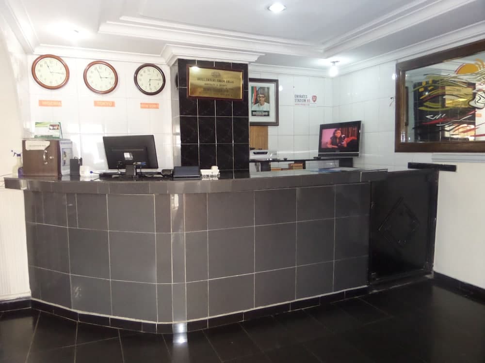 A modern hotel reception area features a sleek black tiled desk, international clocks, and framed artwork, creating a professional atmosphere ideal for travelers seeking efficient check-in services.