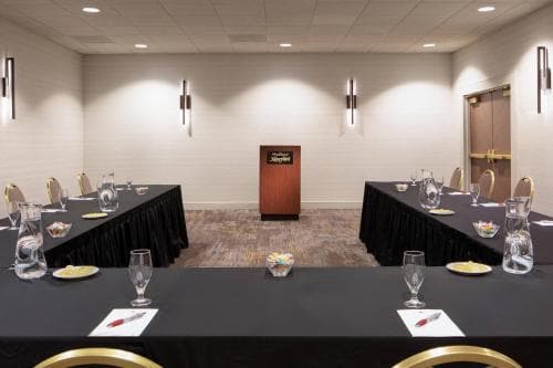 A modern conference room set up for a professional meeting features neatly arranged tables with glasses, notepads, and a podium at the front, ideal for business travelers seeking a venue for presentations or workshops.