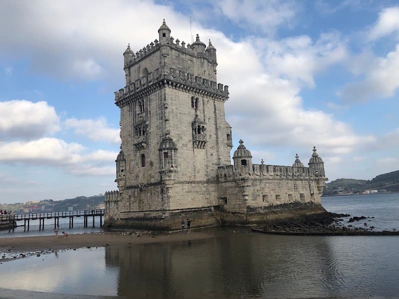 The serene riverside view of the historic Belém Tower in Lisbon, Portugal, under a partly cloudy sky, offers travelers a picturesque spot for cultural exploration and photography.