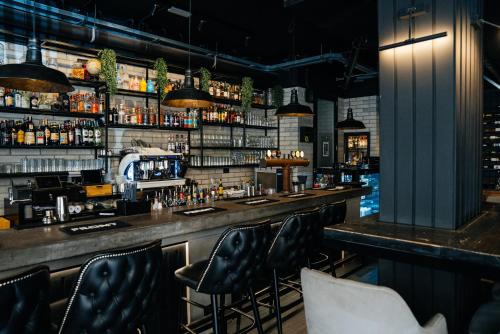 A cozy, dimly-lit bar with sleek black leather stools, an extensive liquor shelf, and modern lighting creates an intimate atmosphere ideal for evening social gatherings or date nights.