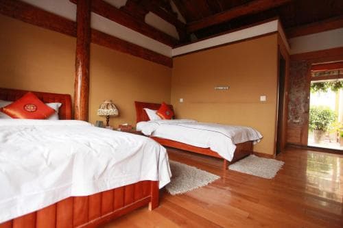 A cozy, warmly lit hotel room with wooden floors, two inviting beds adorned with red accents, and traditional decor creates a serene atmosphere ideal for travelers seeking relaxation and cultural immersion.