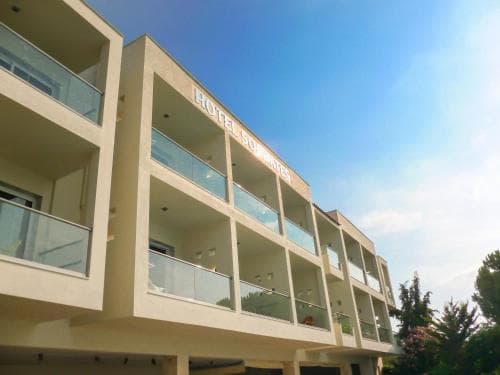 A bright, modern hotel with glass balconies stands under a clear blue sky, offering travelers a serene and inviting accommodation option in a sunny coastal area.