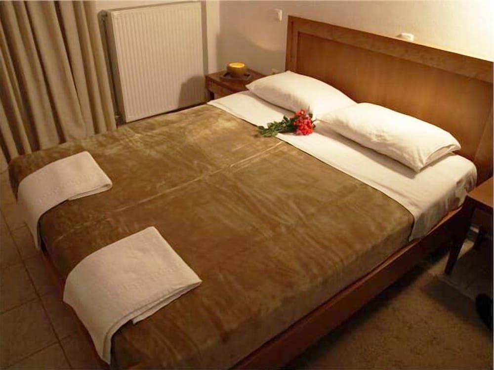 A cozy hotel room features a neatly made bed adorned with fresh towels and flowers, creating a welcoming atmosphere ideal for travelers seeking comfort and relaxation.