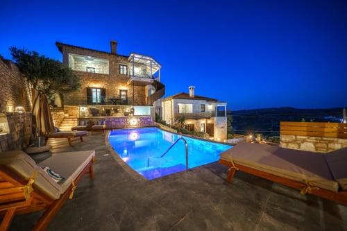 A serene evening at a rustic villa with a glowing pool, cozy lounge chairs, and warm outdoor lighting, ideal for a tranquil luxury retreat.