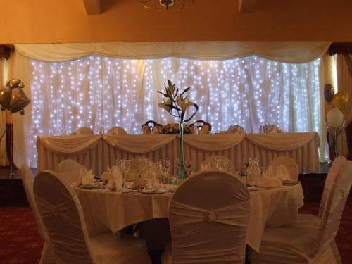 A warmly lit banquet hall adorned with twinkling fairy lights and elegant table settings creates an inviting atmosphere perfect for intimate gatherings or celebrations.